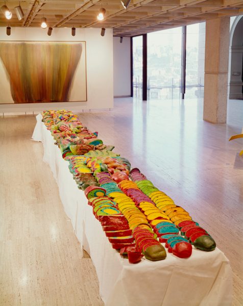 Bright multi-coloured bread, carefully arranged in slices on a long table, inside a gallery.