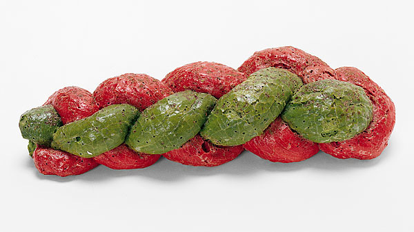 A red and green plaited loaf of bread, shown in close-up on a white background.