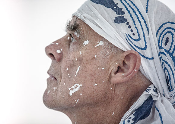 portrait of Richard Long, wearing a headscarf, with his face spattered in white paint