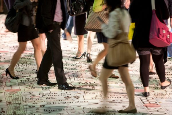 The legs of a small crowd of people, dressed in business attire, walking across a large, hand-drawn street map of the Sydney CBD.